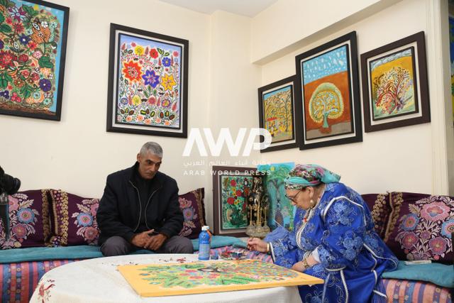 المغربية زهرة أبو علي تجلس مع ابنها رشيد زروق وحولها لوحاتها في منزلها بالعاصمة الرباط حيث لا تزال ترسم لوحات تعكس جذورها وعائلتها والأحداث التي عاشتها على مدار 95 عاما من عمرها (20 مارس آذار 2024)