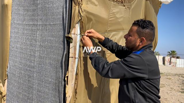  النازح الفلسطيني عماد أبو زيد يقوم بتمتين خياطة خامات المظلات التي تلقى بها المساعدات من الجو للنازحين في قطاع غزة والتي صنع منها خيمة تأويه وعائلته المكونة من 10 أشخاص (14 أبريل نيسان 2024)