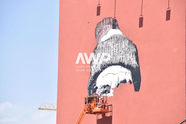 awp - الفنان الألماني هندريك بيكيرش (يمين) أثناء عمله في إعادة تجديد جداريته التي تحمل اسم "الوجه البشوش" في مدينة مراكش بالمغرب، حيث كان قد رسمها للمرة الأولى عام 2015 على واجهة عمارة في المدينة (24 أبريل نيسان 2024)